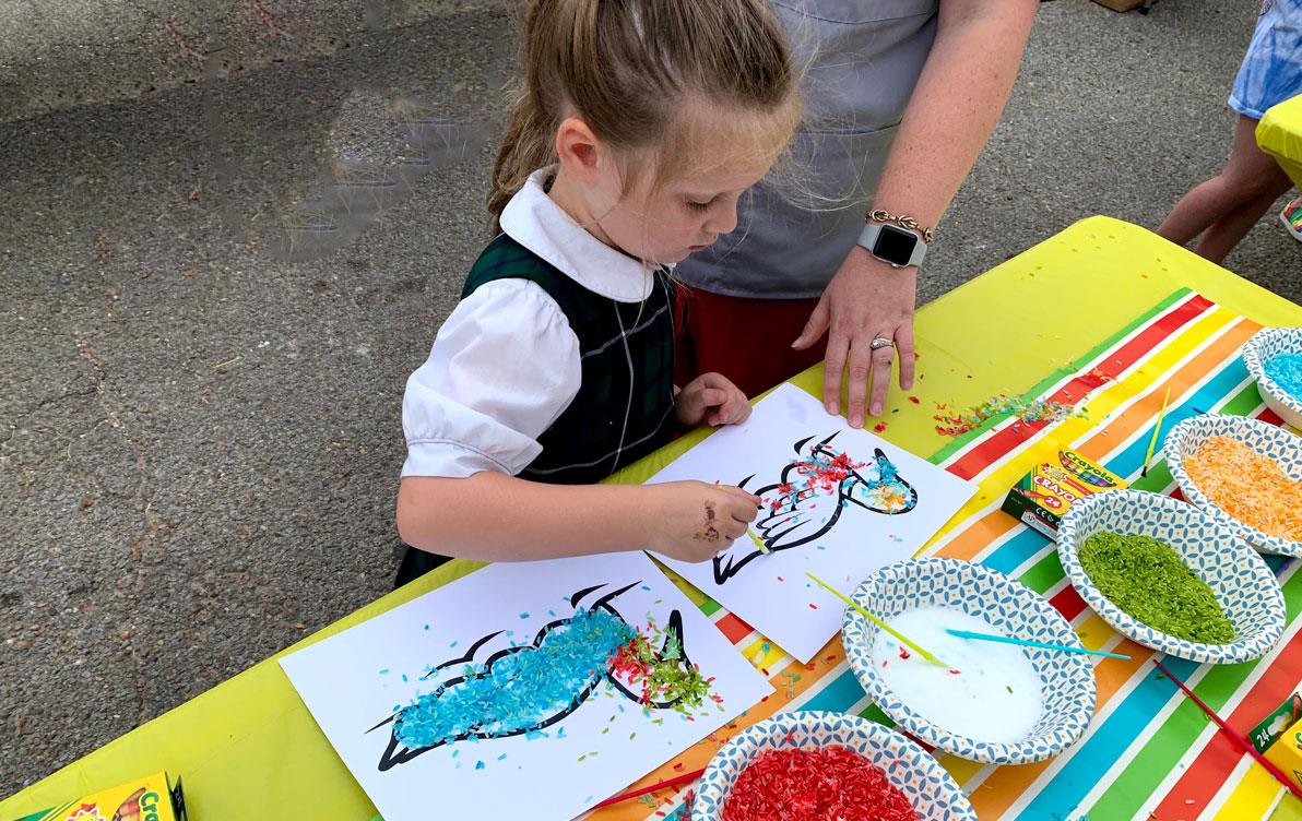 Little girl creates art with colorful rice and crayons