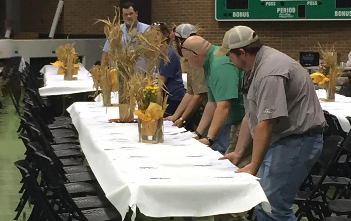 People drag tables with rice centerpieces into place at Annual MS Rice Tasting Luncheon
