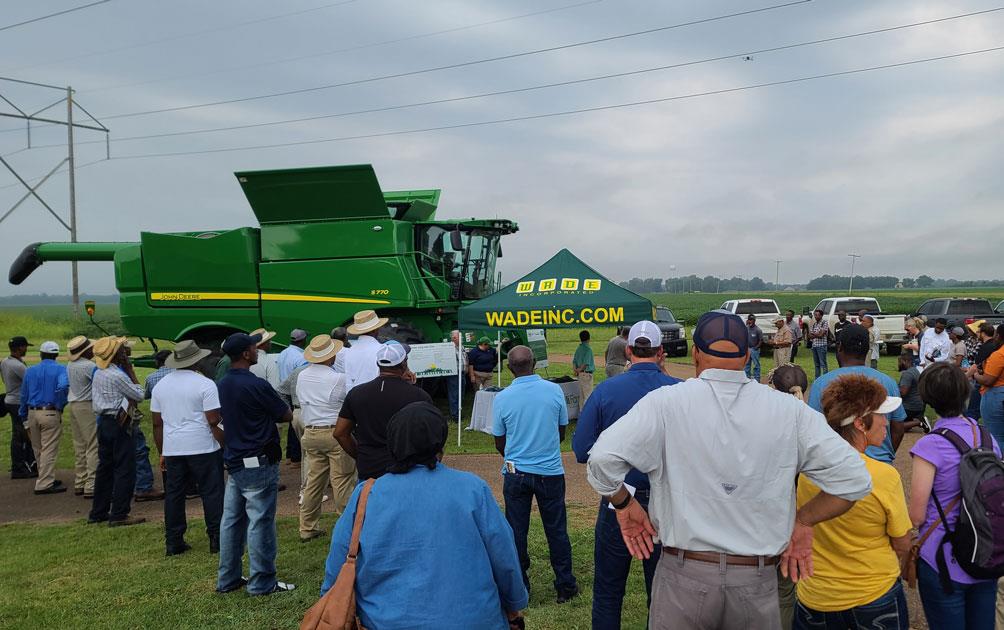 NBGC-Field-Day,-crowd watches drone demo, John Deere combine in background