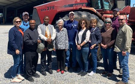 Group shot of people standing outside in front of red combine