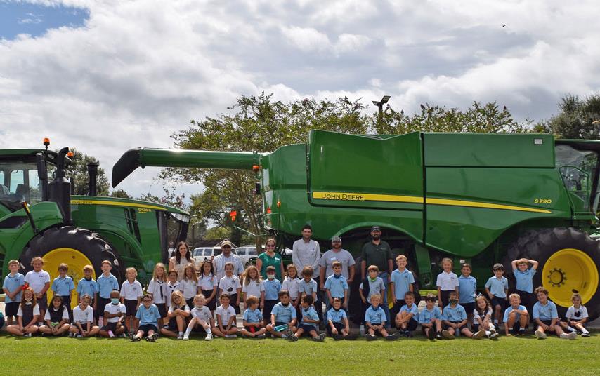 Elementatry school students pose for group shot in front of green combine