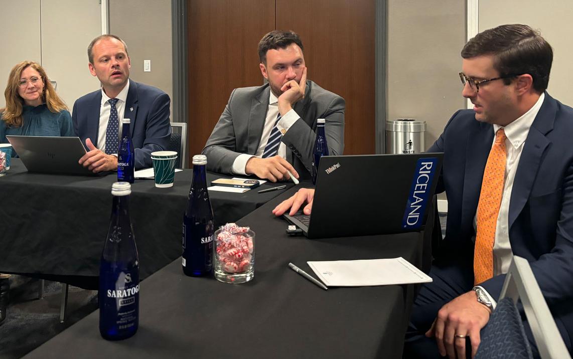 Adam-Shea-meets-with-European-Delegates, everyone wearing business attire, seated at conference table