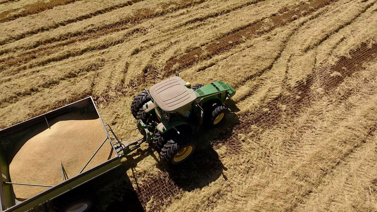 Overhead shot of tractor pulling grain cart in harvested field