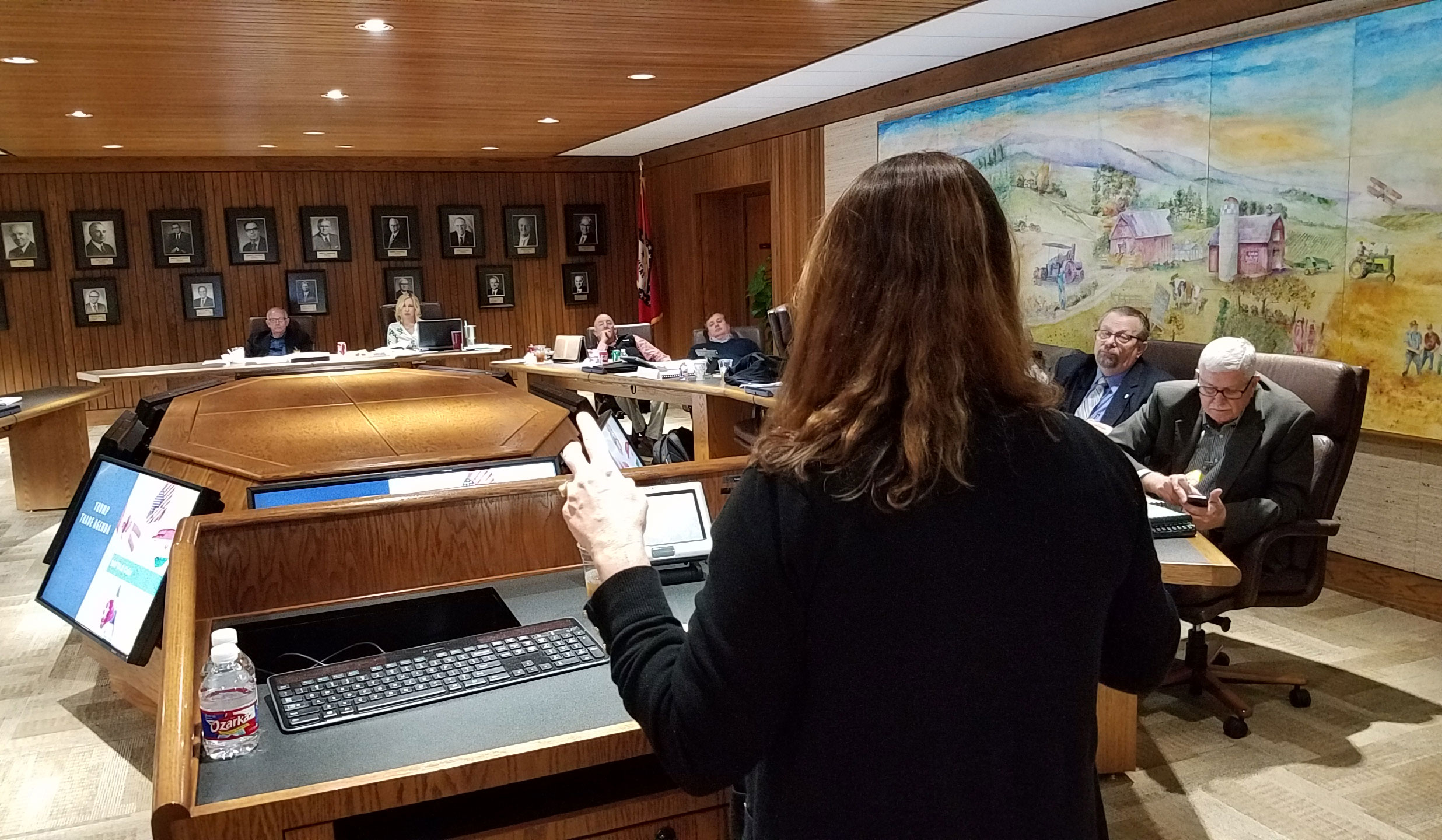 Betsy Ward stands at podium giving presentation at AR board meeting